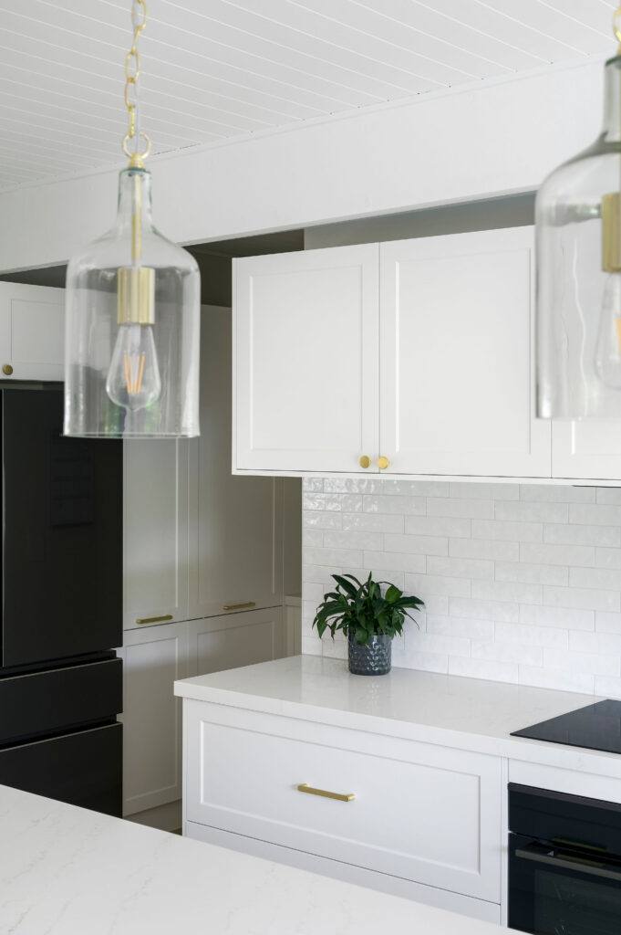 Modern kitchen renovation with white built-in cabinets and a marble subway tile splashback.